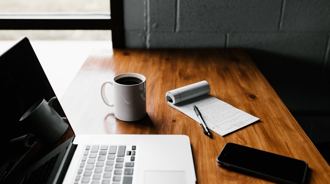 Content writer workspace with laptop, research notes, and morning coffee for SEO writing